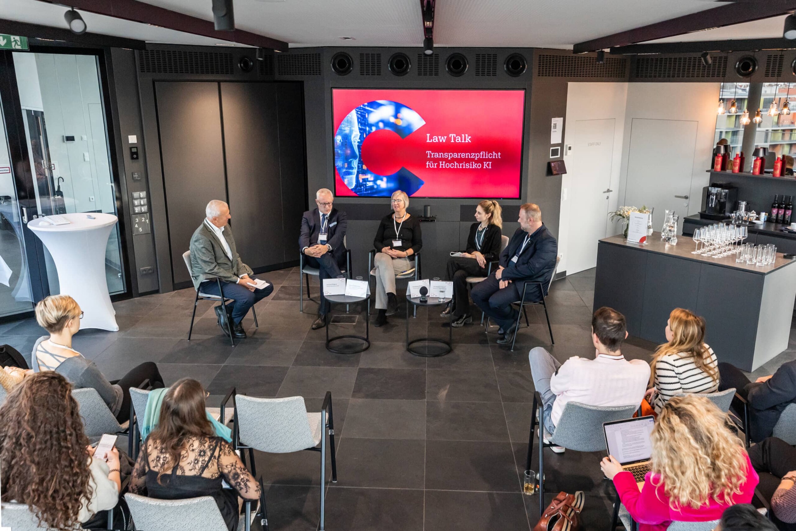 Die Podiumsdiskussion in einer Spannenden Perspektive von leicht oberhalb aus dem Publikum fotografiert. vlnr Georg Mittmair, Gerhard Wagner, Maria Reiffenstein, Madeleine Müller, Christof Tschohl